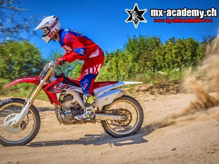 Entraînement sensations fortes avec son propre équipement : pilote au casque blanc sur une Honda, le sable gicle derrière la roue arrière Entraînement sensations fortes avec son propre équipement : pilote au casque blanc sur une Honda, le sable gicle derrière la roue arrière
