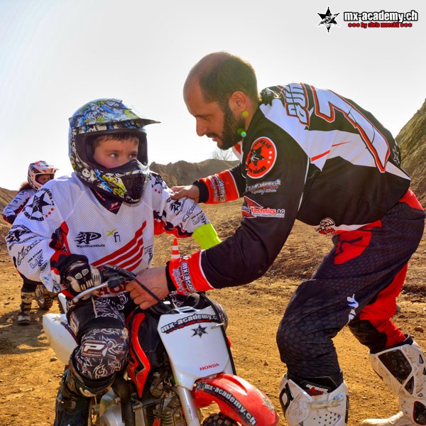 Moto cross pour les jeunes avec un moniteur professionnel : le moniteur de la MX-Academy montre au jeune pilote la bonne position au guidon